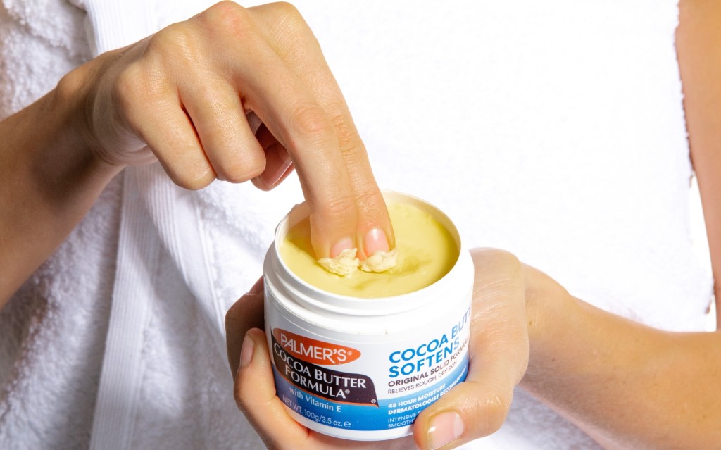 dipping fingers in palmers cocoa butter solid jar to show texture